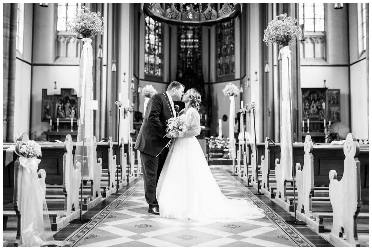 Braut und Bräutigam küssen sich in der Kirche in Mönchengladbach