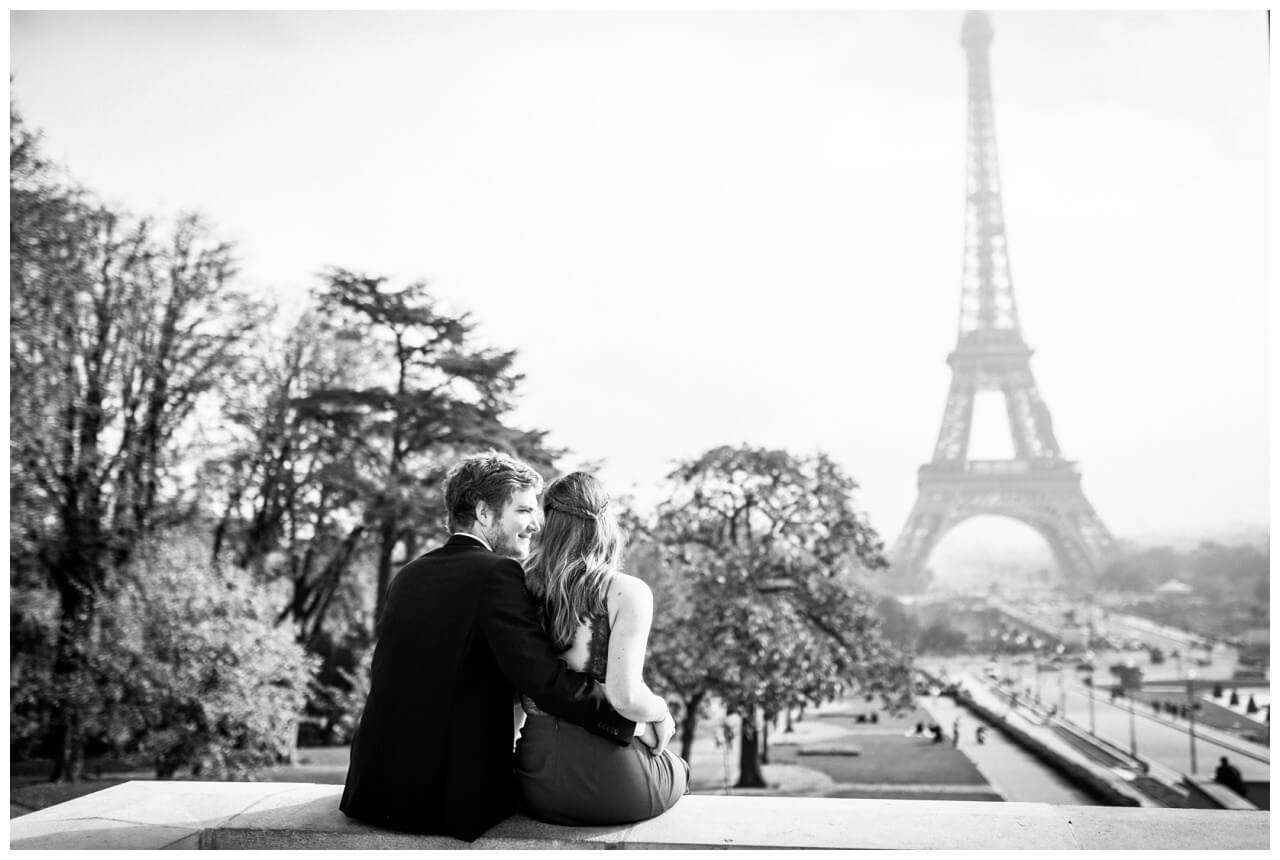 Paarshooting in Paris, das Paar sitzt auf einer Mauer und sieht auf den Eiffelturm.