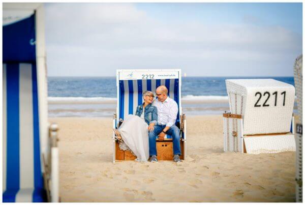 Hochzeit auf Sylt, das Brautpaar kuschelt im Strandkorb.