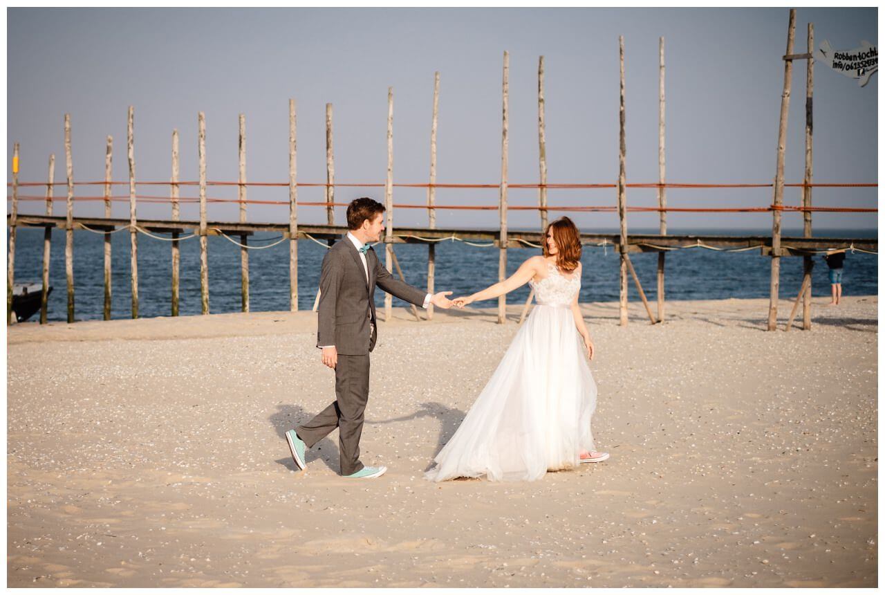 Hochzeitsbild am Strand, das Brautpaar läuft am Strand entlang
