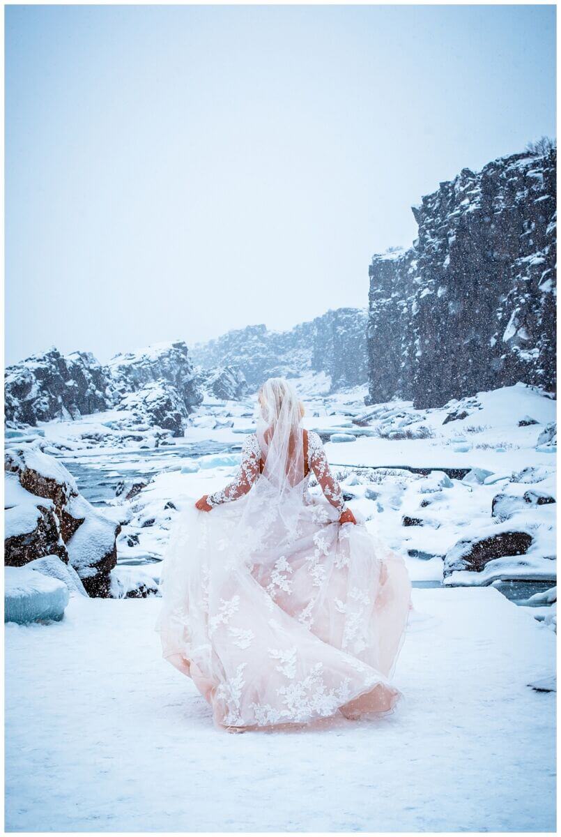 Braut mit Ausblick auf eisigen Bergen bei ihrer Hochzeit auf Island.